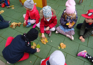 Dzieci przeliczają liście zgodnie z liczbą oczek na kostce do gry.